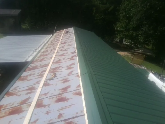 Old rusted panels beside newly installed green metal roofing — Wind Damage Roof Repair by Roofing Brothers in Parris Island