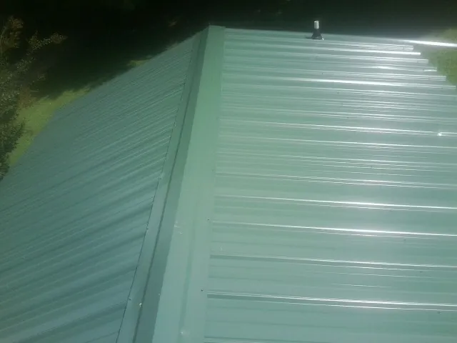 New green metal panels meeting at the ridge of a roof — Flat Roof Repair work by our crew in Parris Island