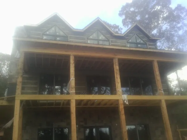 Dormers and porch framing on a large log home under construction — Roof Coating work by our crew in Parris Island