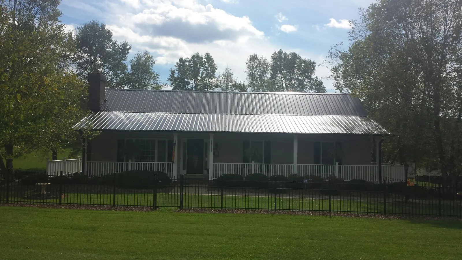 Gray metal roof on a brick ranch with a full width front porch — Gutter Guard Installation work by our crew in Parris Island
