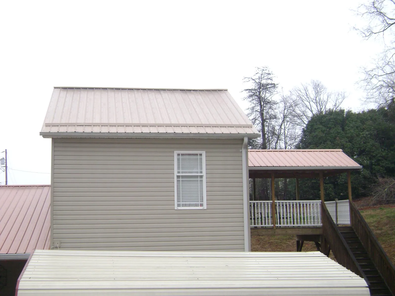 Tan metal roofs on a two story addition and attached porch, from a Roof Replacement job in Parris Island