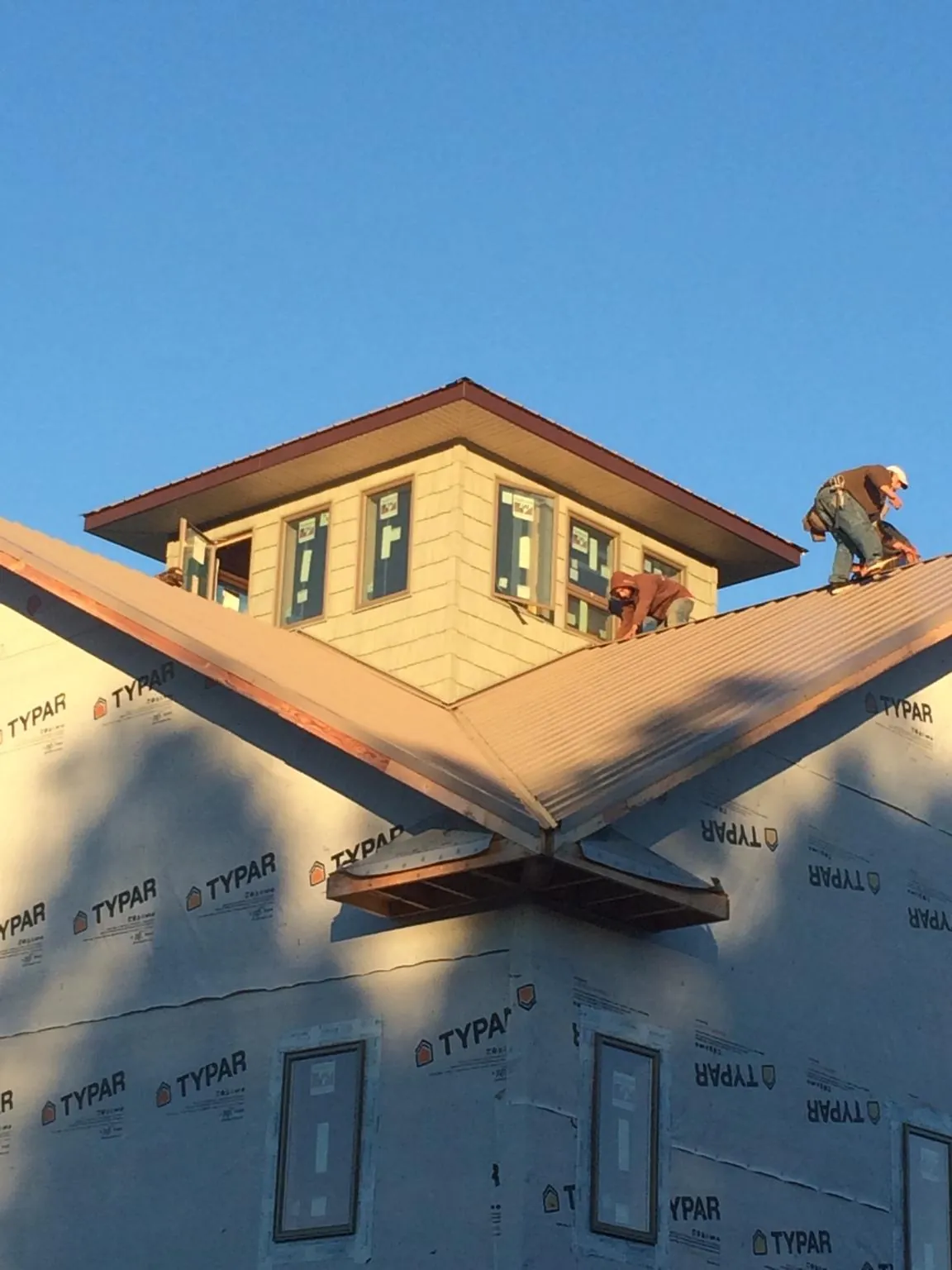 Roofers working around a rooftop cupola on a new metal roof at sunset — Roof Waterproofing in Parris Island by Roofing Brothers